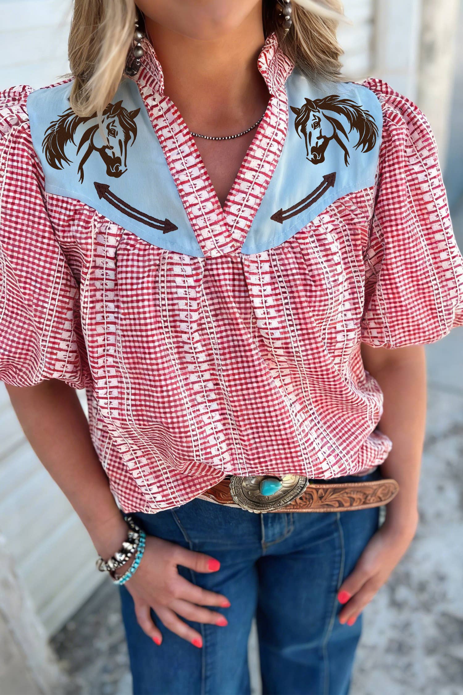 Red checkered blouse with horse designs on a blurred background
