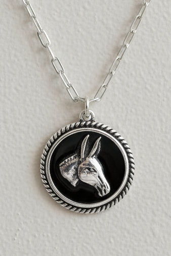 Silver necklace with a pendant featuring an animal design on a wooden surface