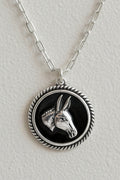 Silver necklace with a pendant featuring an animal design on a wooden surface