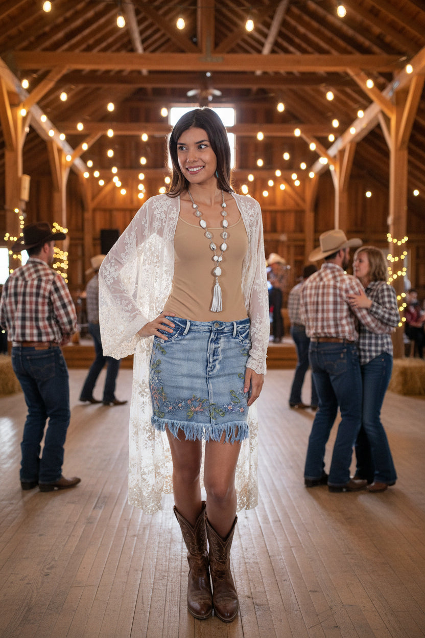 Woman wearing a beige top, denim skirt, and lace cardigan on a white background