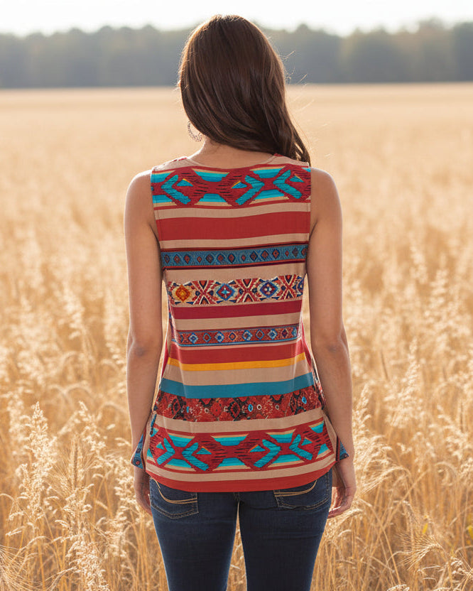 Woman wearing a colorful patterned sleeveless top standing in a field.