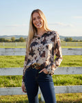 Woman wearing a patterned blouse and jeans on a white background